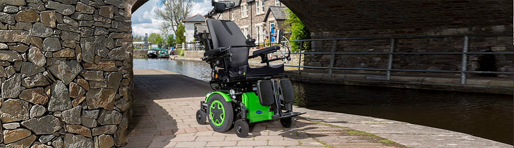 An empty bright green electric wheelchair sits by a river inside a tunnel