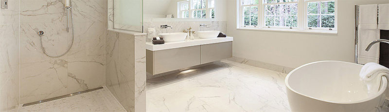 A beautiful cream marble level access bathroom with curved bath and double basin
